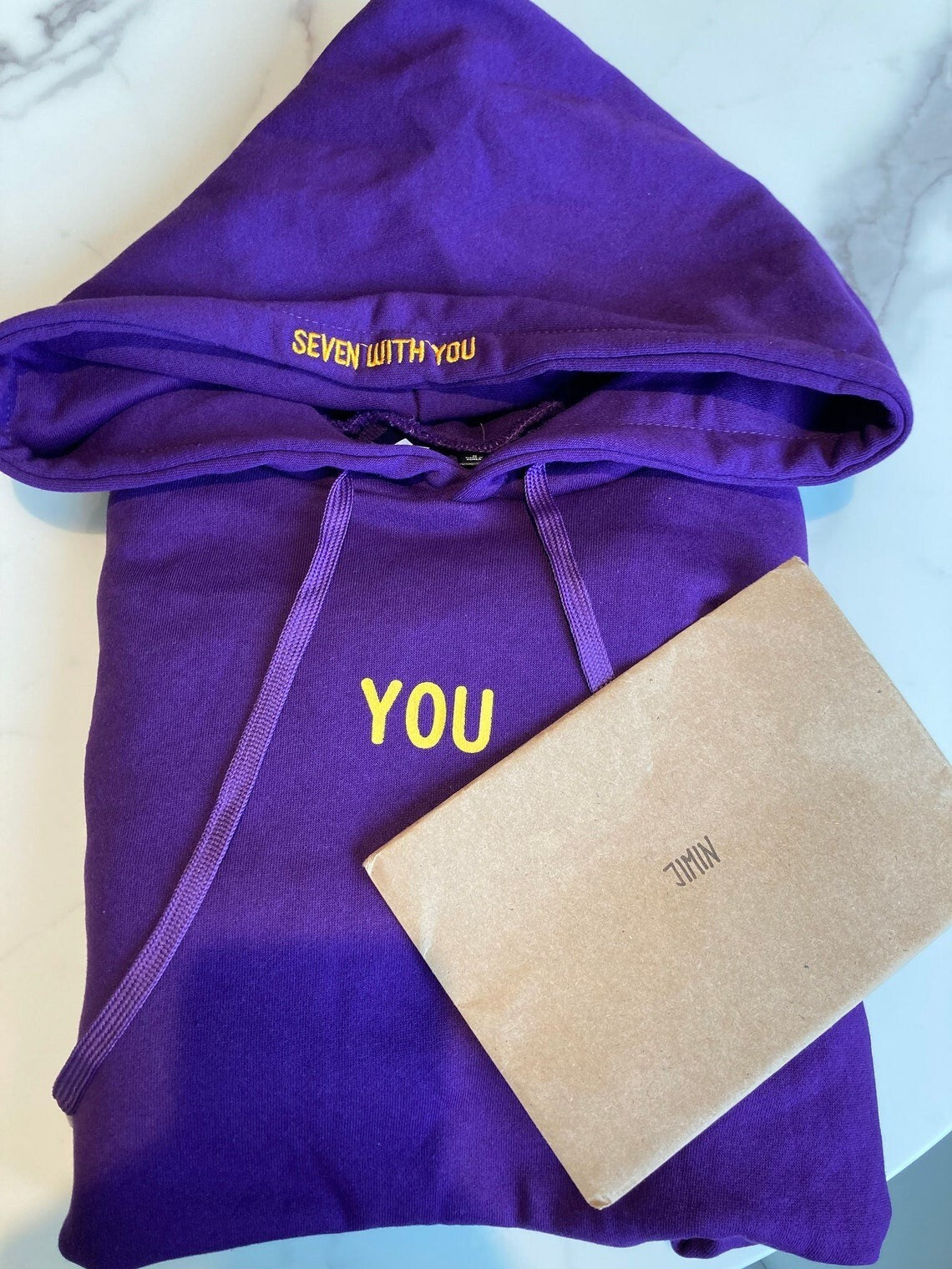 Seven With You lettering on the purple hood and yellow YOU chest design